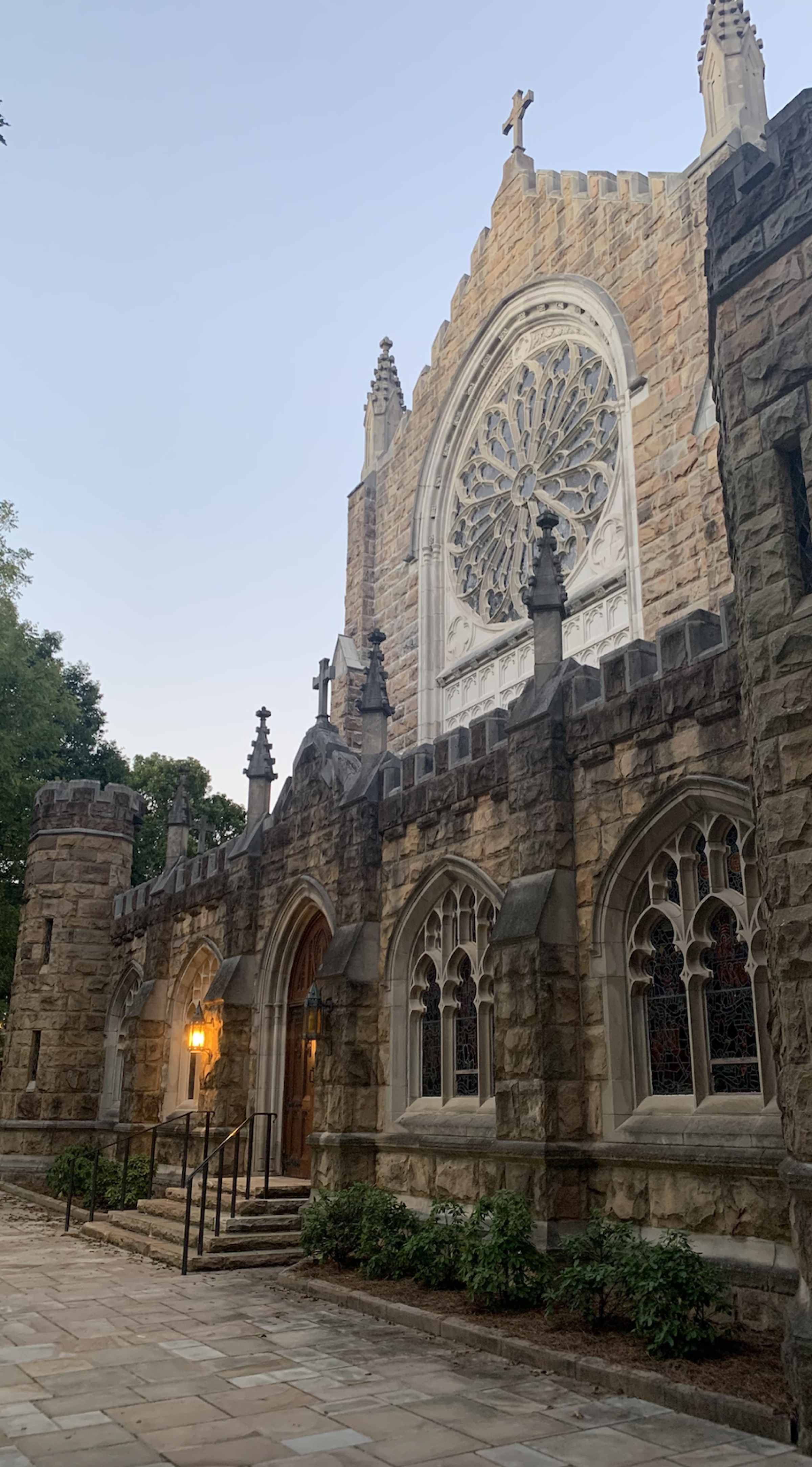 All Saints' Chapel at the University of the South — Gothic stone facade with rose window at dusk on the Sewanee campus
